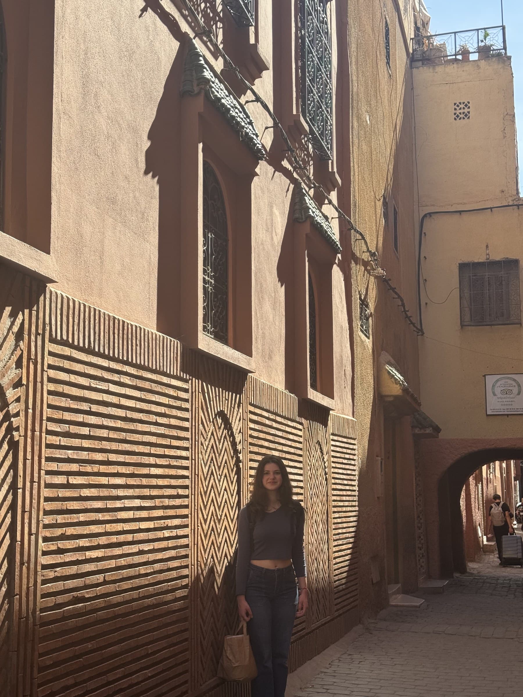 Viajera en callejón de la medina de Marrakech con pared de ladrillos en patrón geométrico tradicional