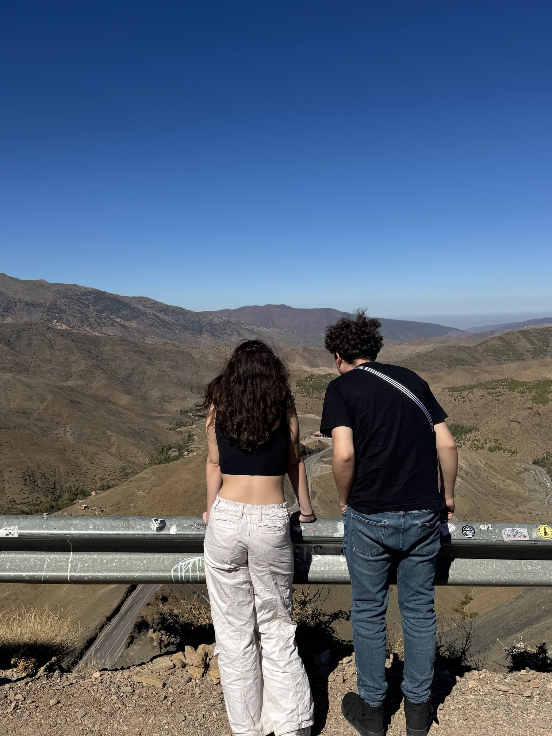 Dos viajeros contemplan el paisaje del Alto Atlas desde un mirador en el puerto de Tizi N'tichka, Marruecos
