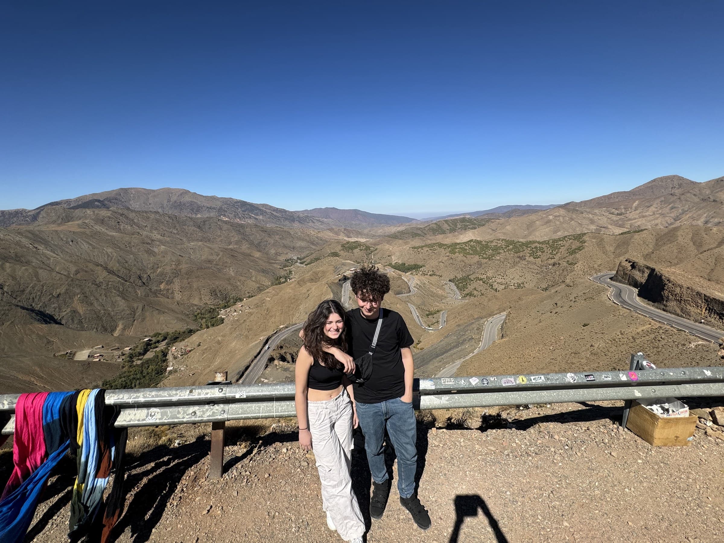 Pareja de jóvenes en el mirador del puerto de Tizi N'tichka con las curvas del Alto Atlas al fondo, Marruecos