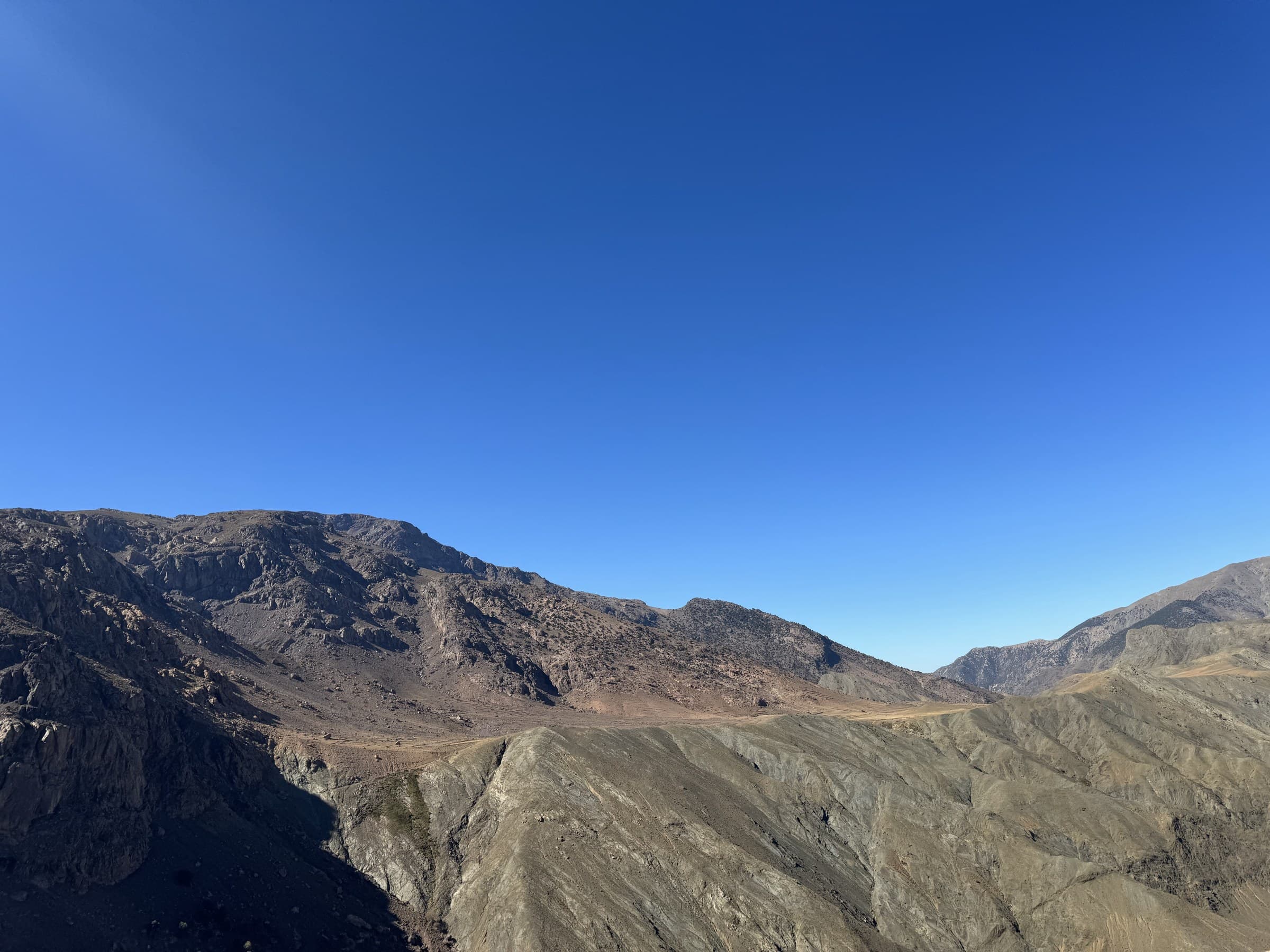 Paisaje árido del Alto Atlas marroquí con cumbres rocosas y cielo azul despejado