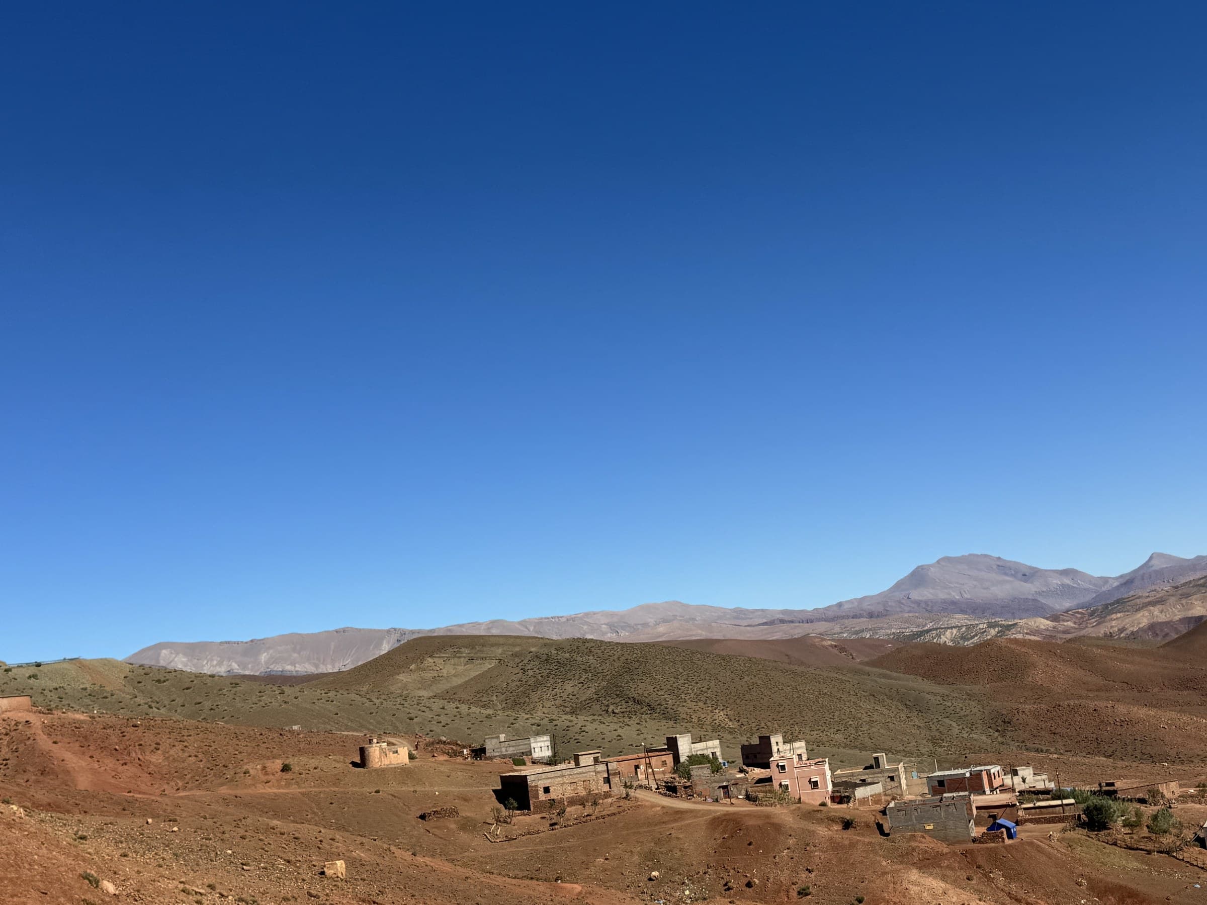 Aldea bereber en el Alto Atlas marroquí con casas de barro y montañas áridas bajo cielo azul intenso