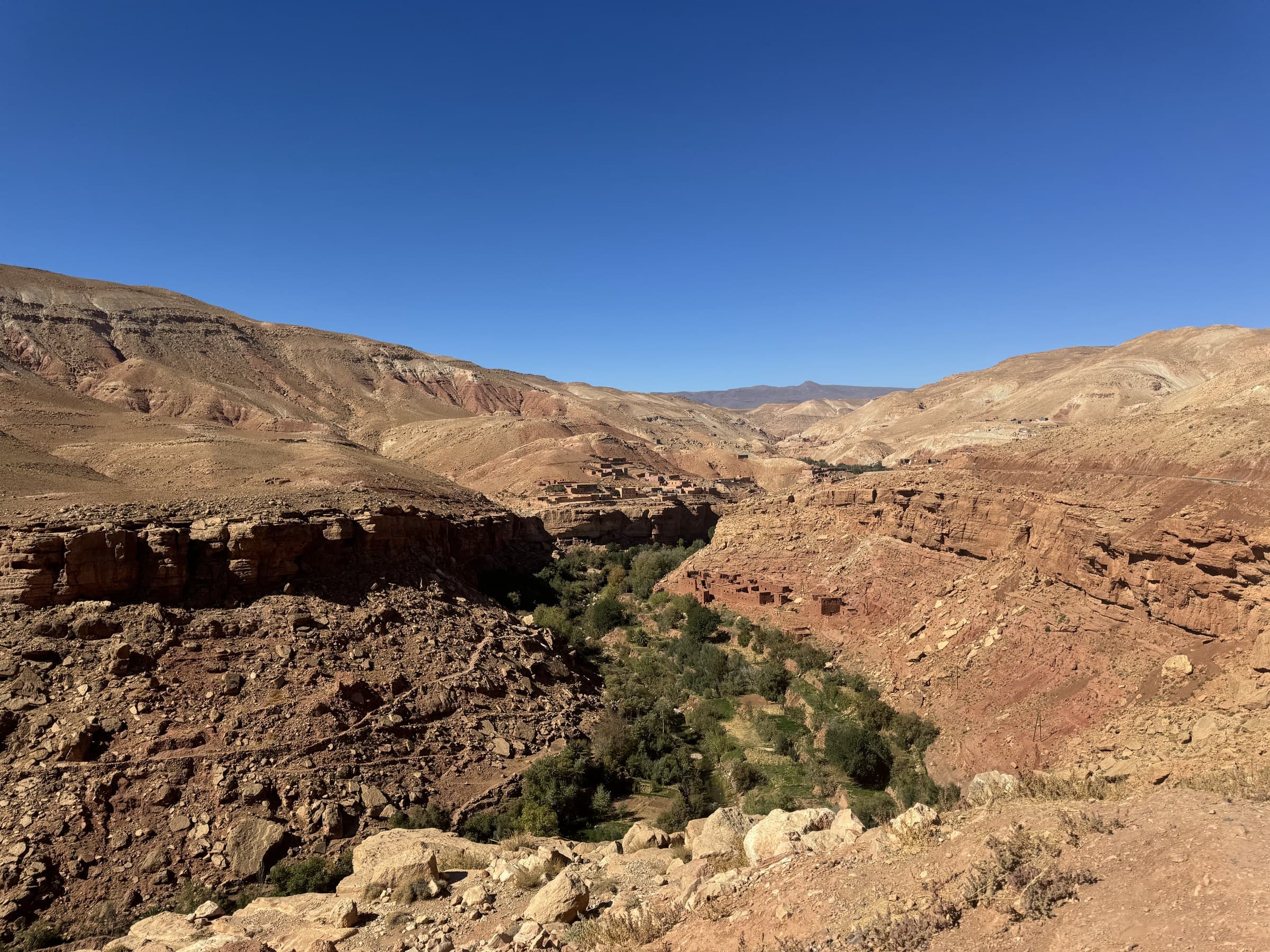 Valle del Dadés en Marruecos con aldea bereber de tierra roja y vegetación verde entre cañones rocosos bajo cielo azul