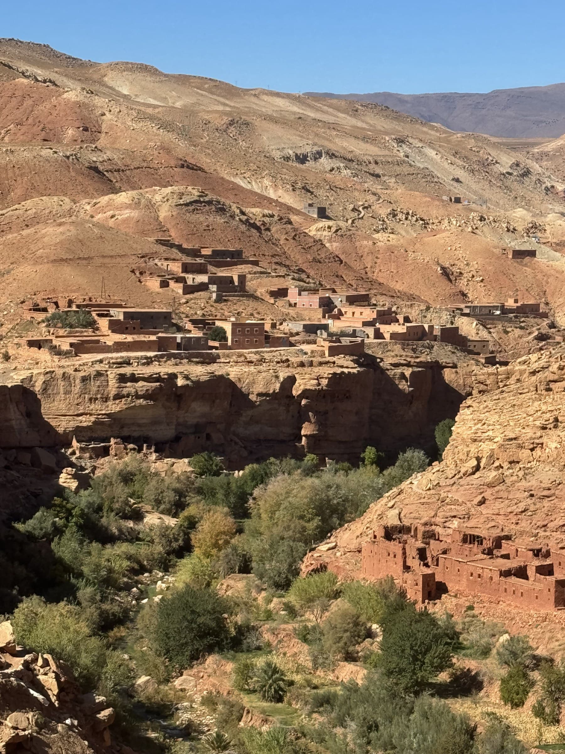 Aldea bereber de adobe sobre acantilados rojos en el Valle del Dadés, Marruecos, con vegetación en el cañón