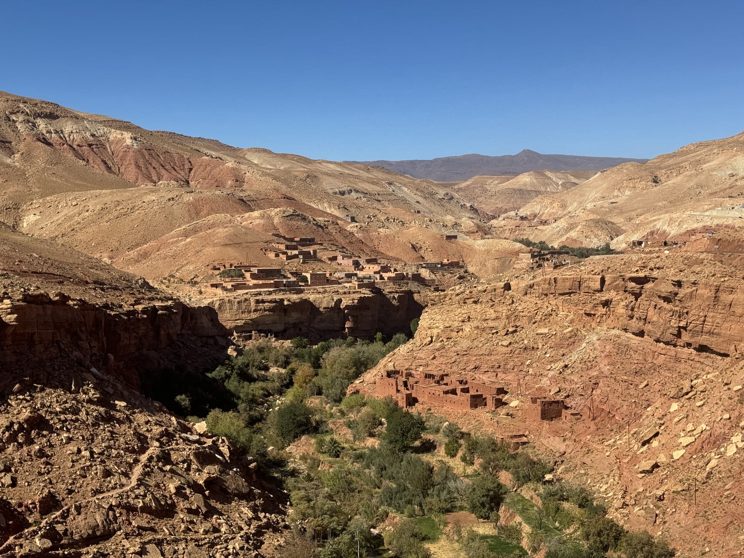 Valle del Dadés con aldea bereber de adobe rojo entre acantilados rocosos y vegetación verde, Marruecos
