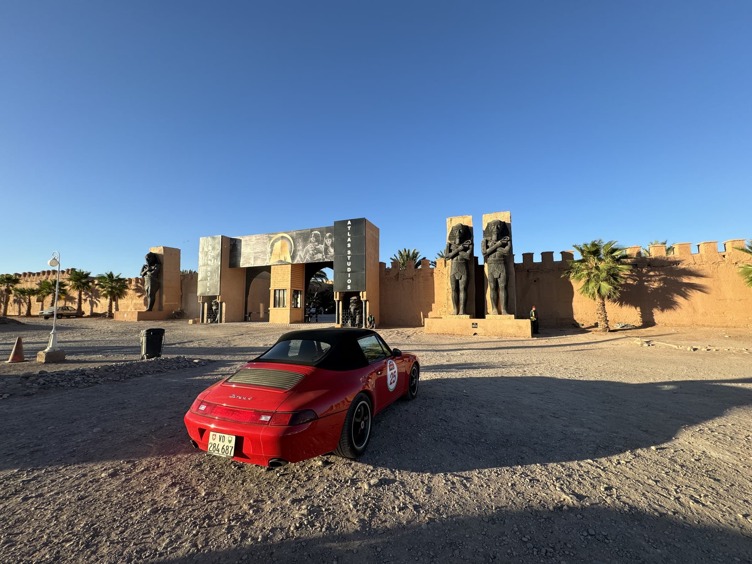 Porsche rojo descapotable frente a la entrada de Atlas Studios en Ouarzazate, Marruecos, con estatuas faraónicas