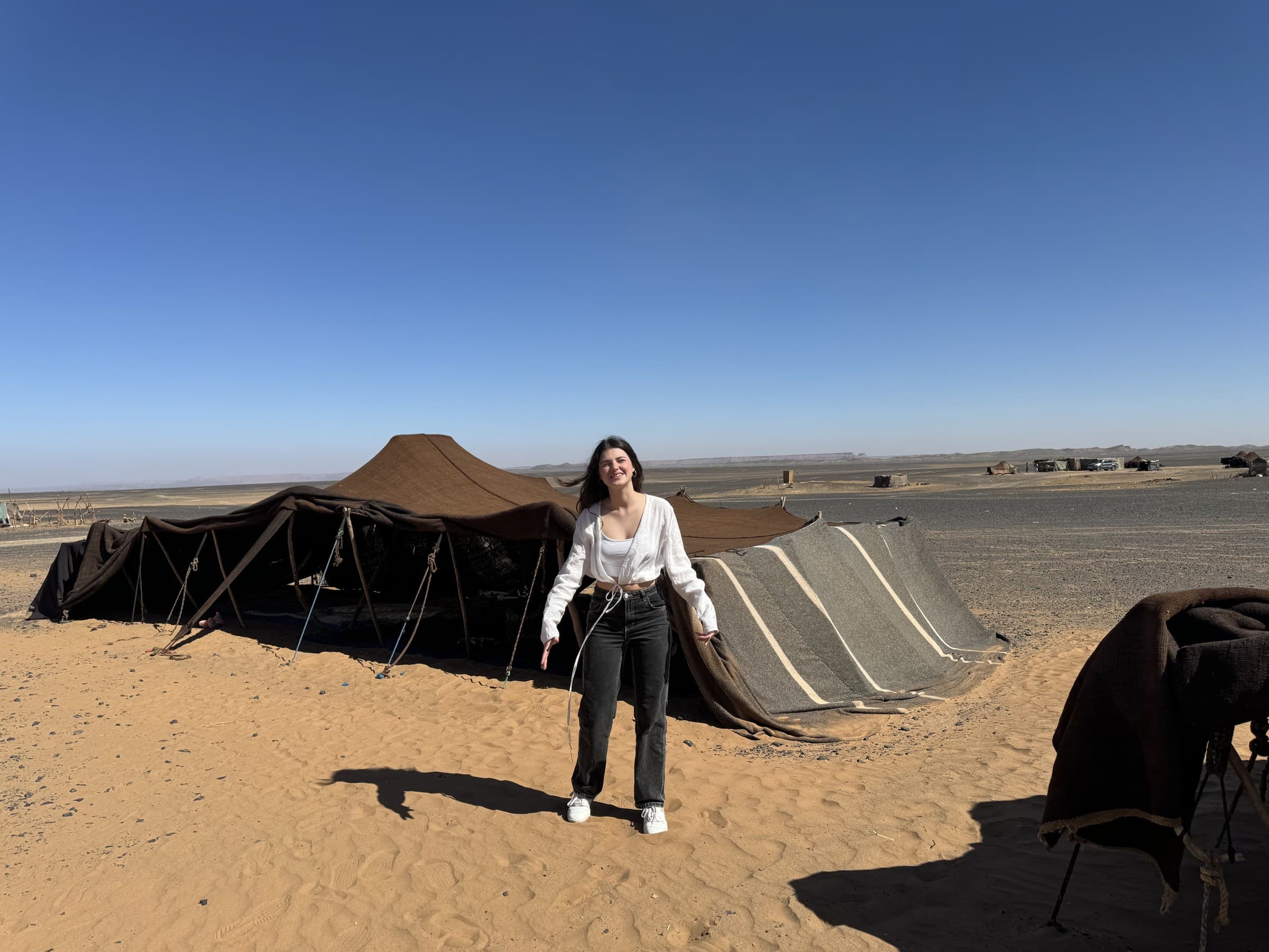 Viajera frente a jaima bereber tradicional en el desierto del Sahara de Marruecos bajo cielo azul