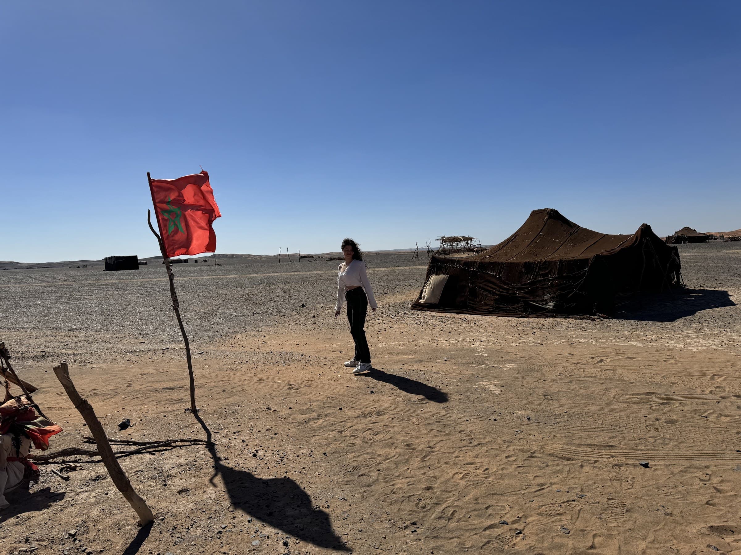 Viajera junto a tienda nómada beréber y bandera de Marruecos en el desierto del Sahara