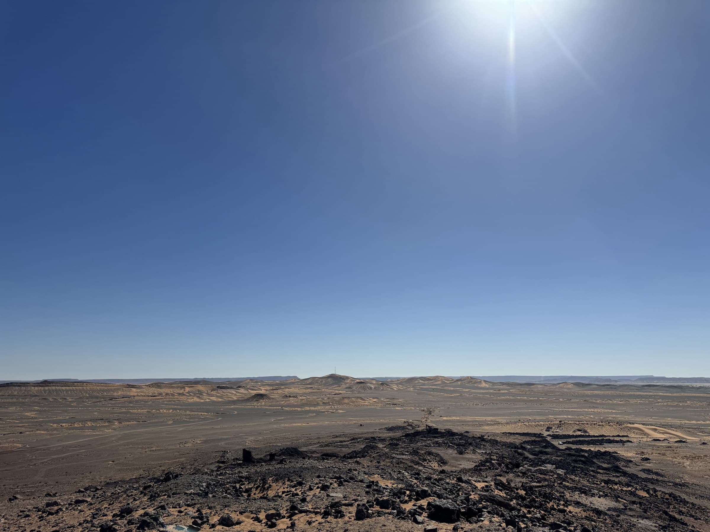 Paisaje desértico rocoso del Sahara marroquí bajo un cielo azul intenso con sol brillante al mediodía