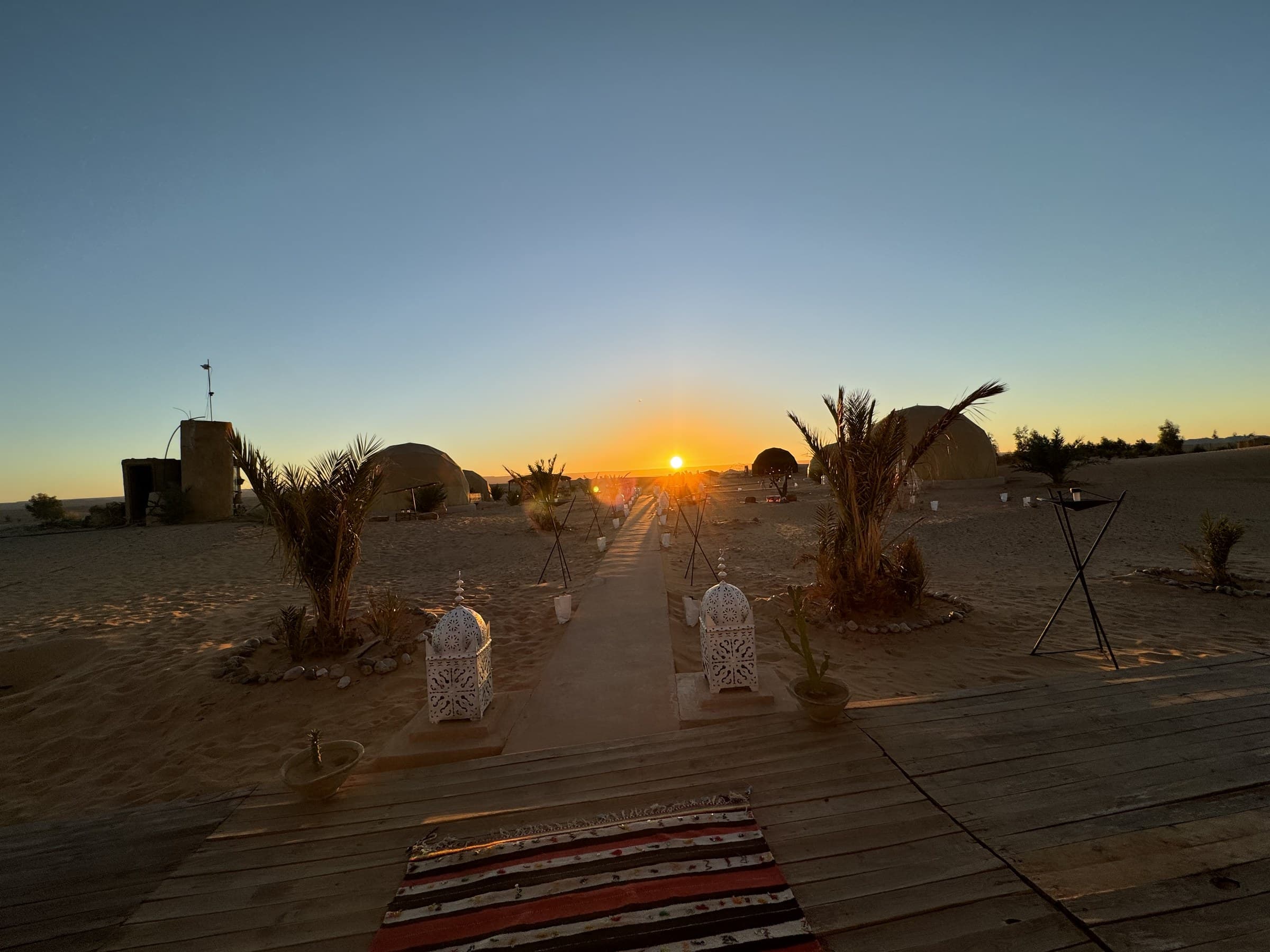Campamento de lujo en el desierto de Merzouga al atardecer con linternas marroquíes y tiendas jaima