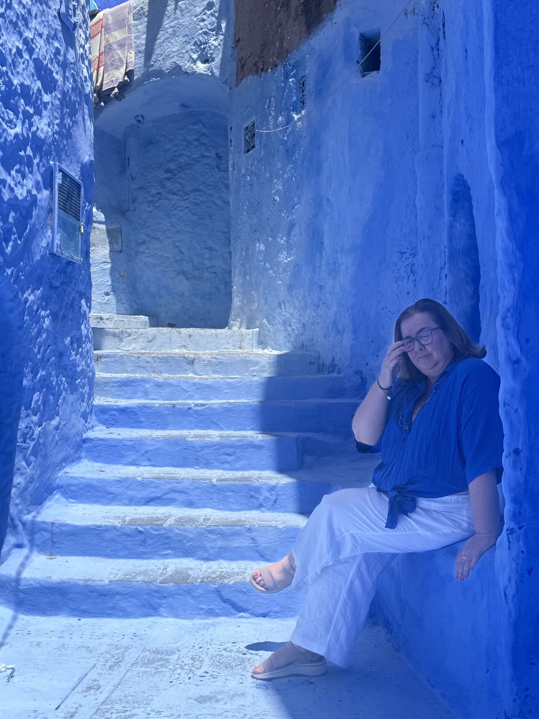 Viajera sentada en los escalones azules de un callejón de la medina de Chefchaouen, Marruecos