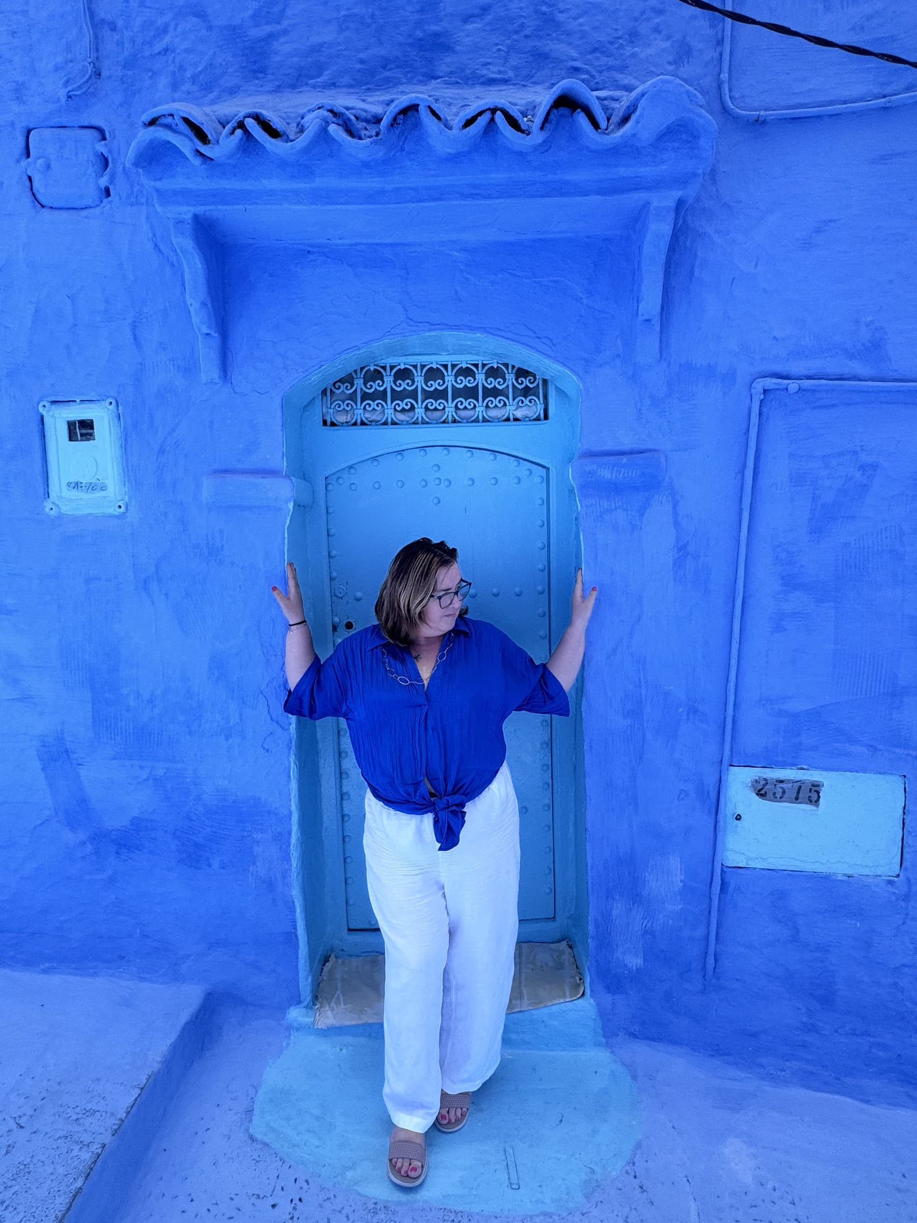 Viajera posando ante una puerta azul con forja en la medina de Chefchaouen, Marruecos
