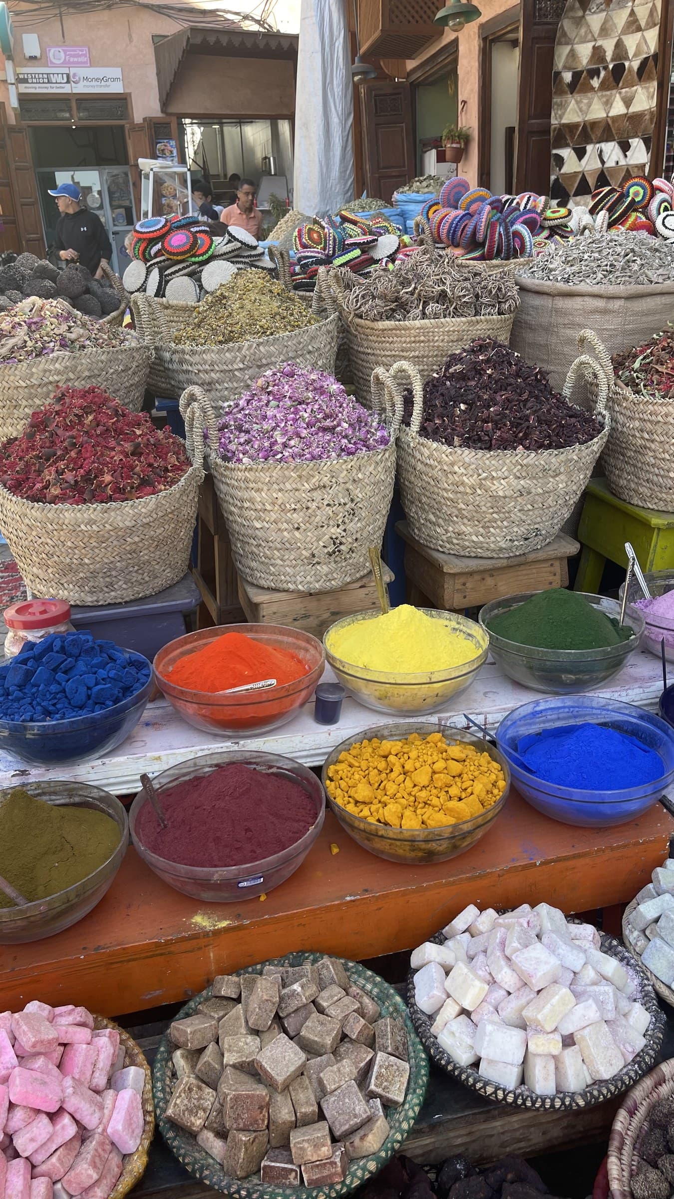 Puesto de especias y hierbas en el zoco de Marrakech con coloridos polvos y flores secas en cestas