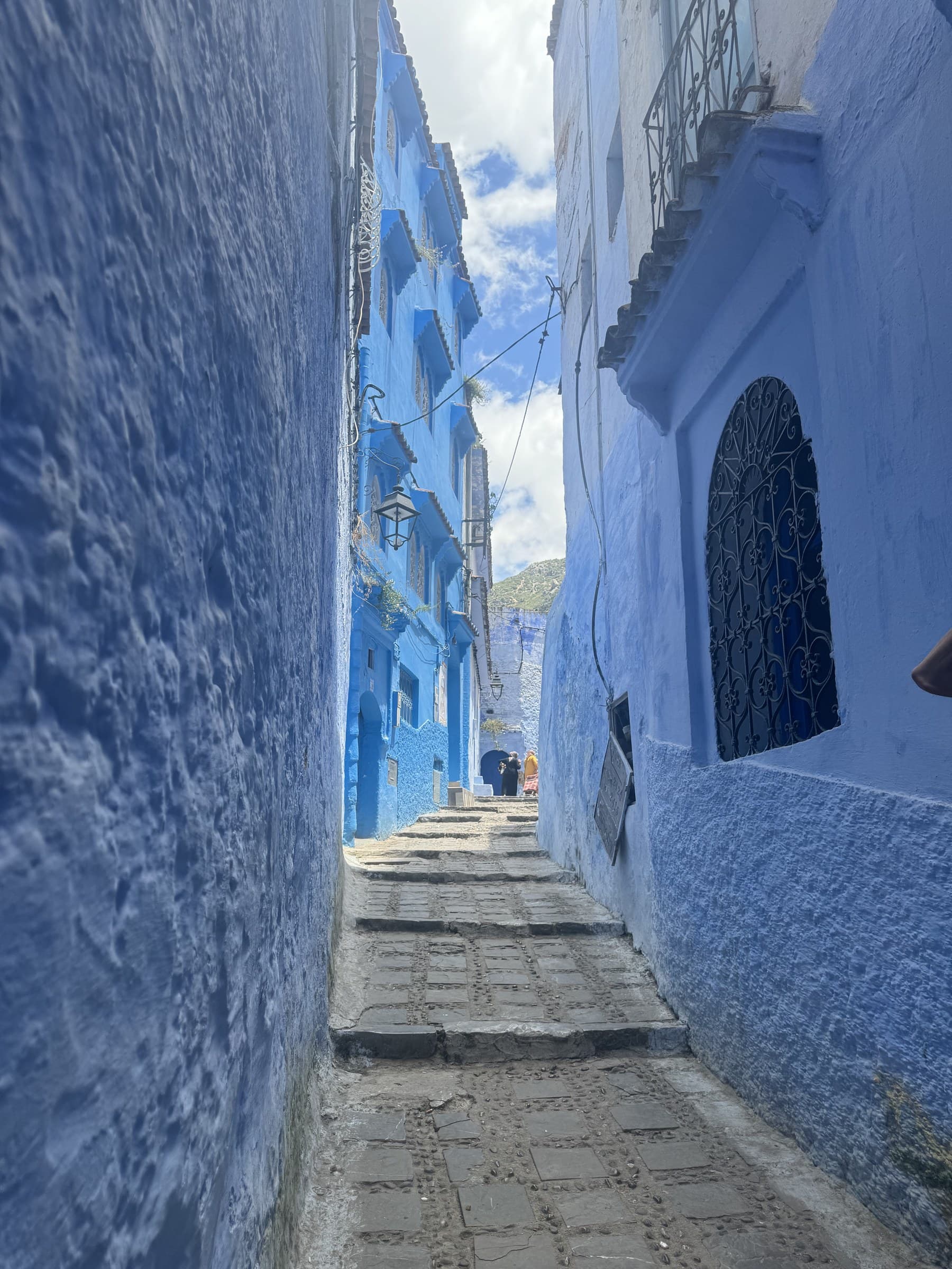 Callejón azul de Chefchaouen con escaleras de piedra y paredes pintadas de azul índigo, Marruecos