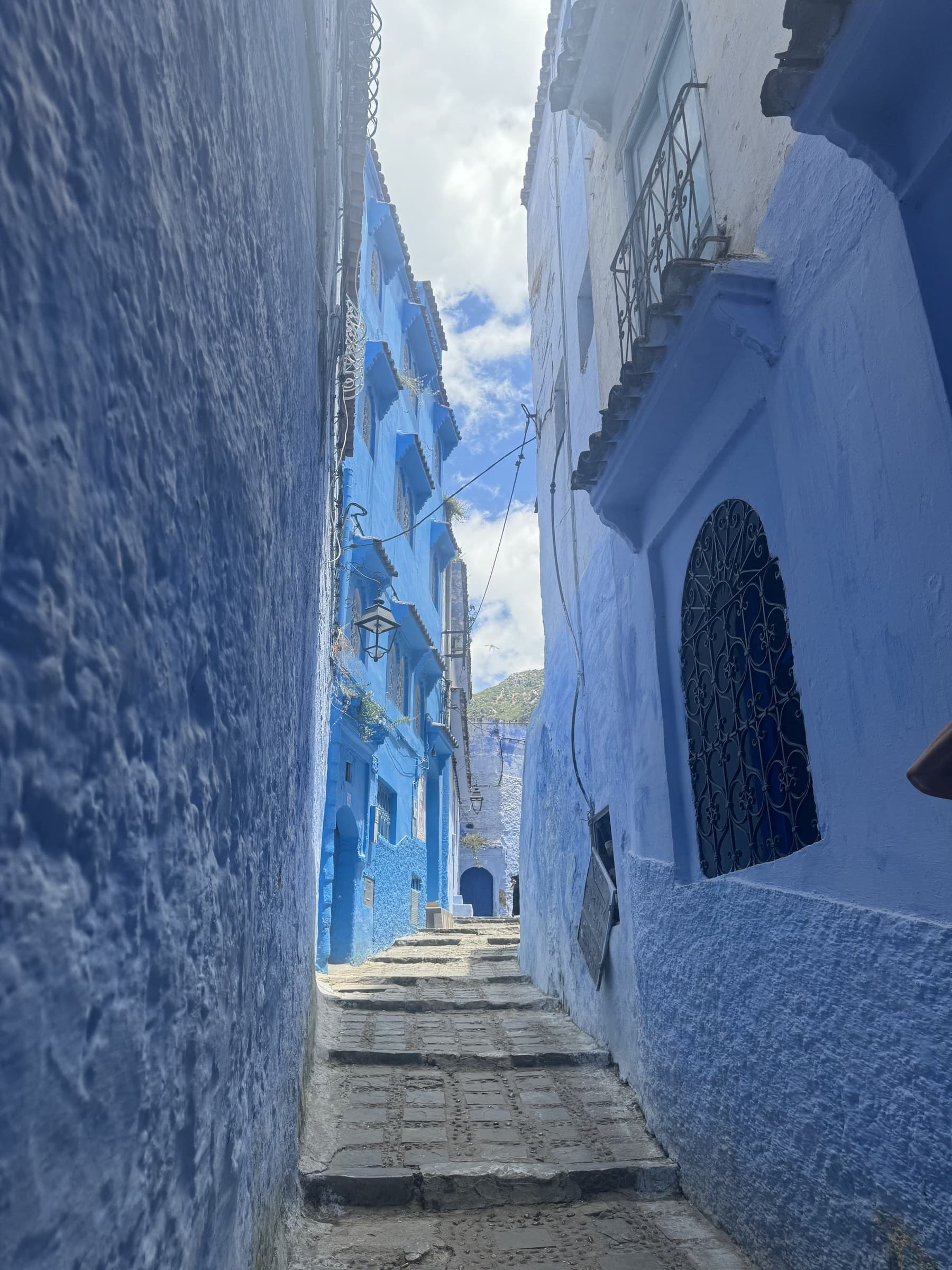 Callejón azul de Chefchaouen con escaleras de piedra y paredes pintadas de azul índigo, Marruecos