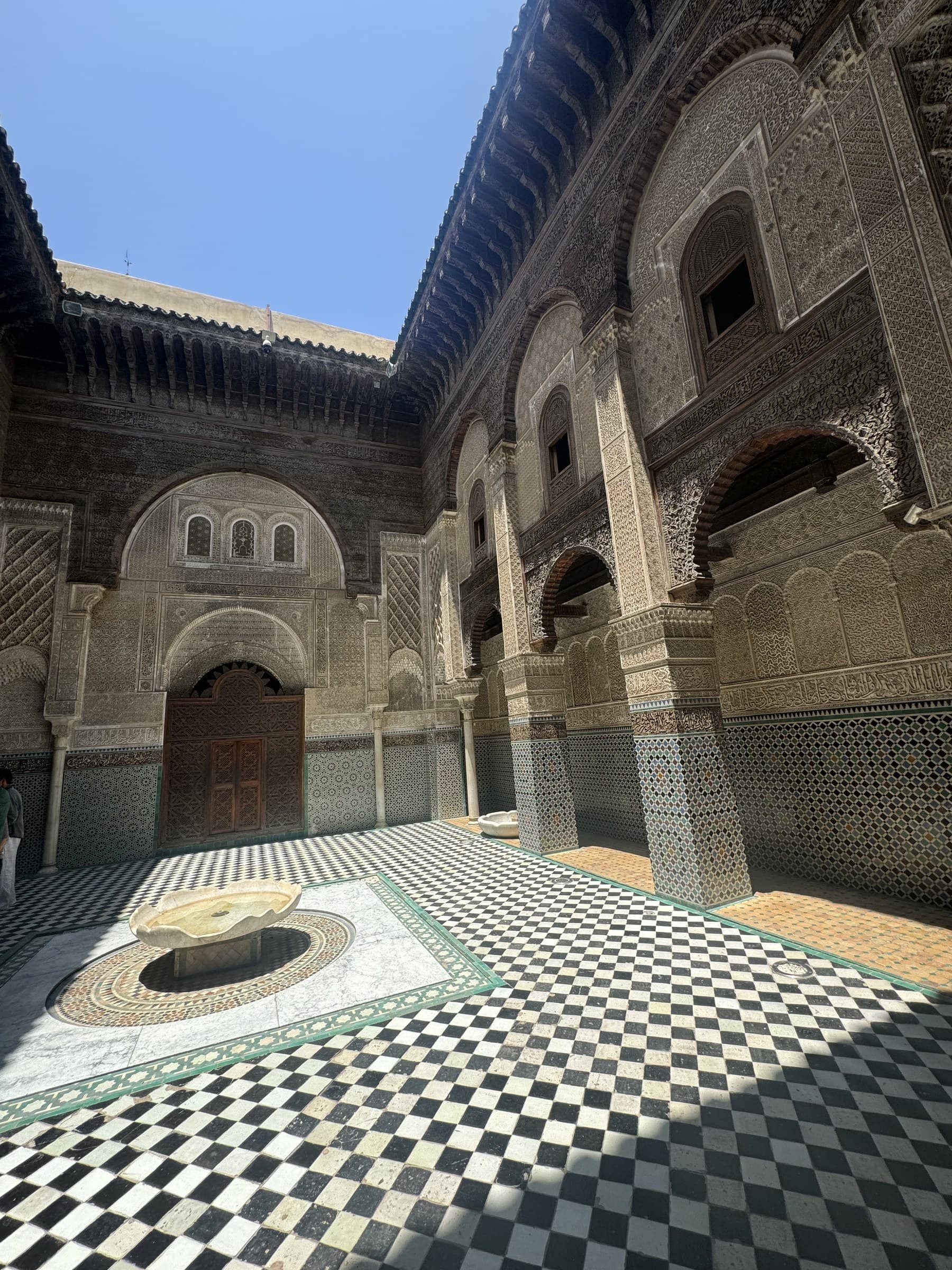 Patio interior de la madrasa Bou Inania de Fez con suelo de mosaico ajedrezado y ornamentación islámica