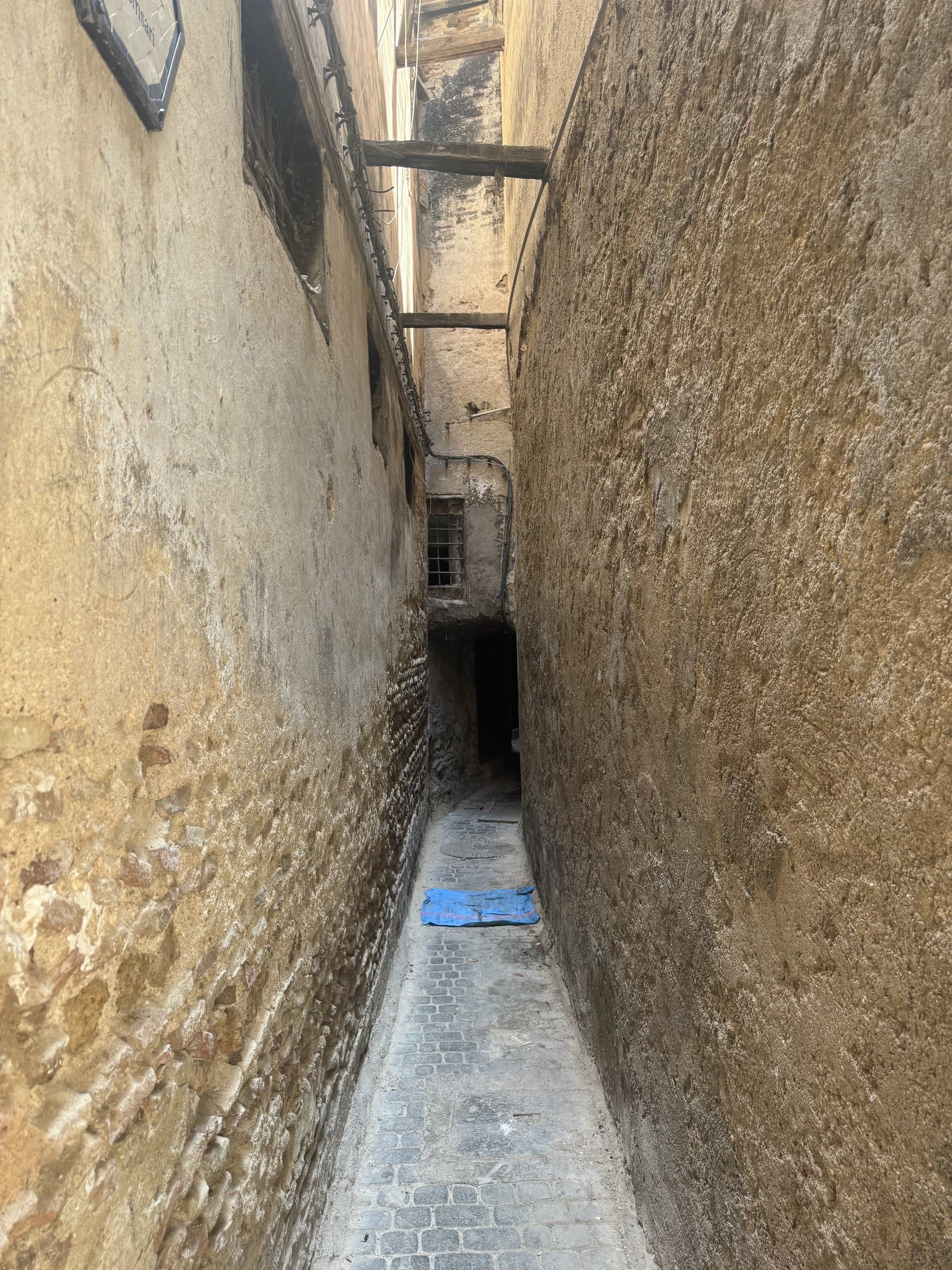 Callejón estrecho de piedra en la medina antigua de Fez, con paredes de barro milenarias y adoquines