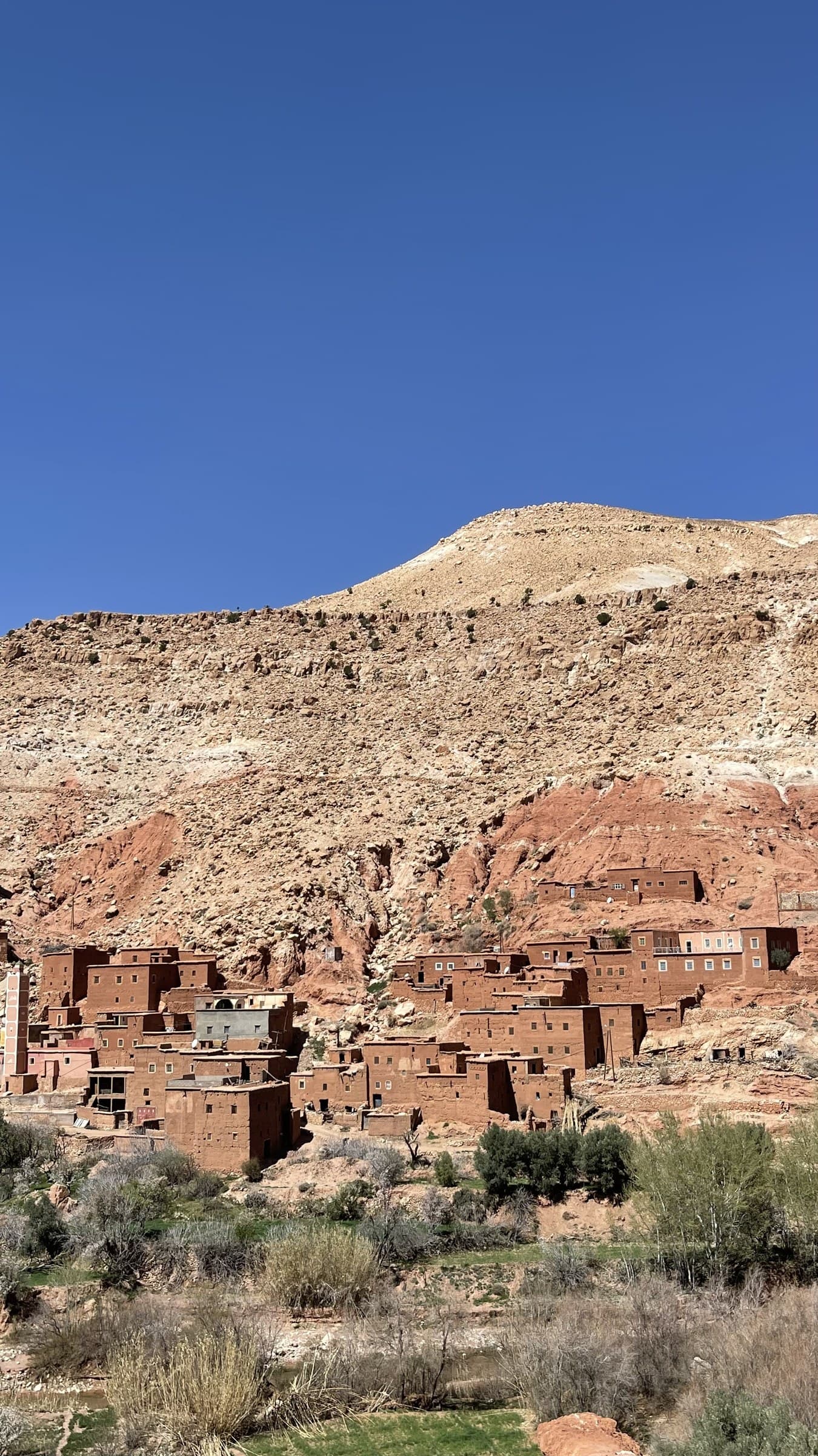Aldea bereber de adobe rojo enclavada en las rocas del Valle del Dadés, Marruecos, bajo cielo azul intenso