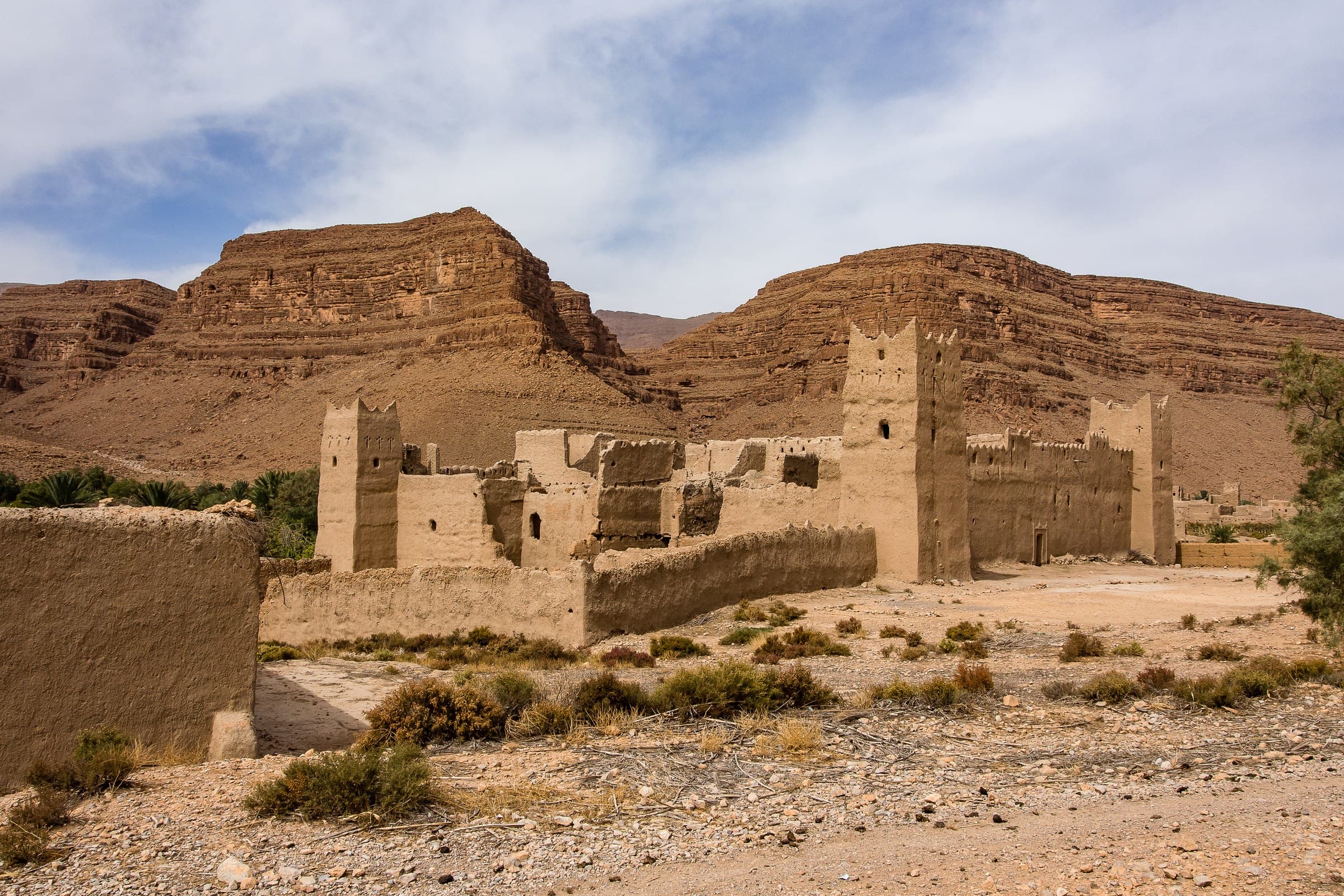 Kasbah de barro en ruinas en el Valle del Ziz, Marruecos, con imponentes acantilados rojizos al fondo
