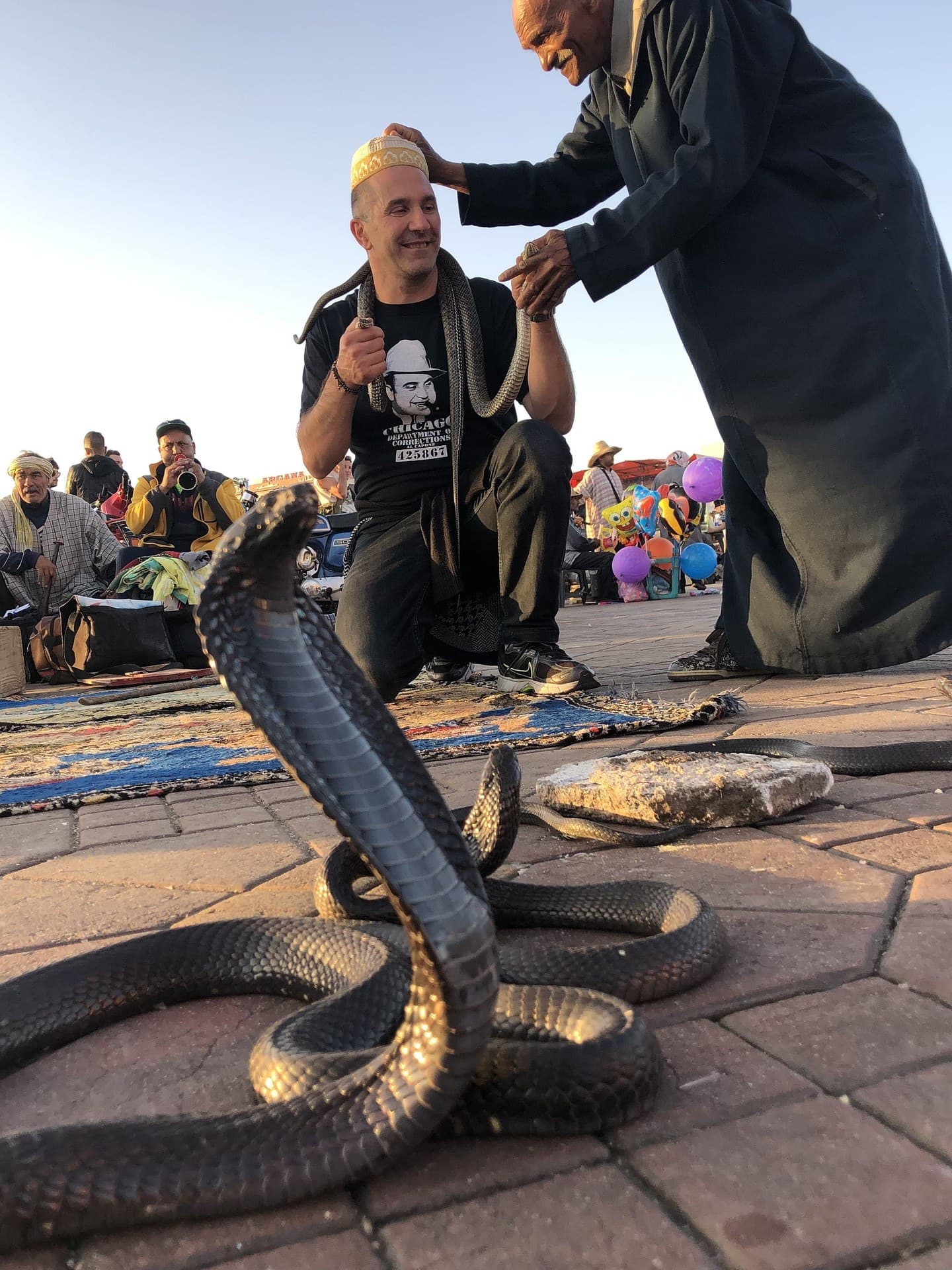 Encantador de serpientes con cobra erguida en la plaza Jemaa el-Fna de Marrakech al atardecer
