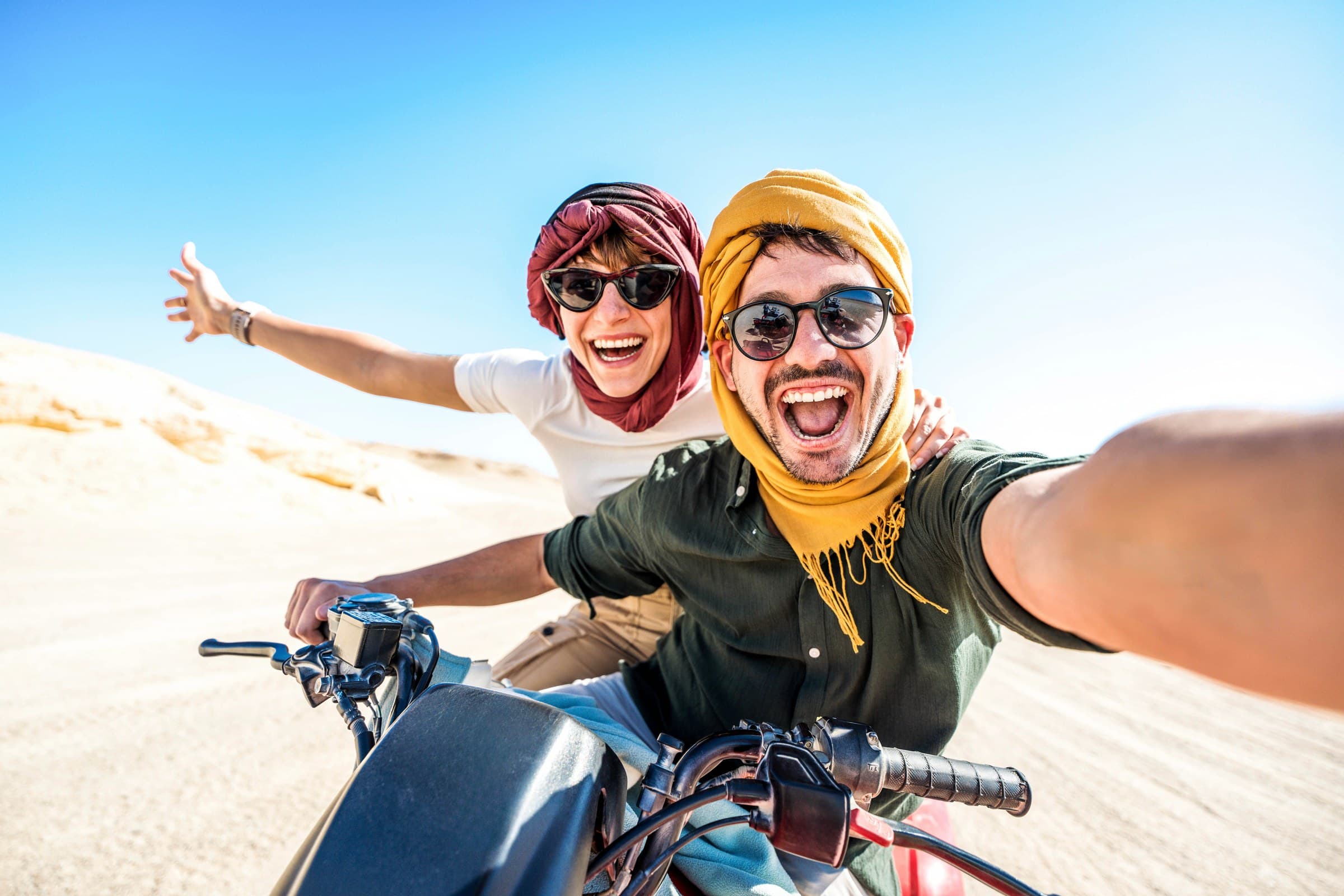Pareja de viajeros en quad por las dunas del desierto del Sahara en Marruecos con turbantes bereberes