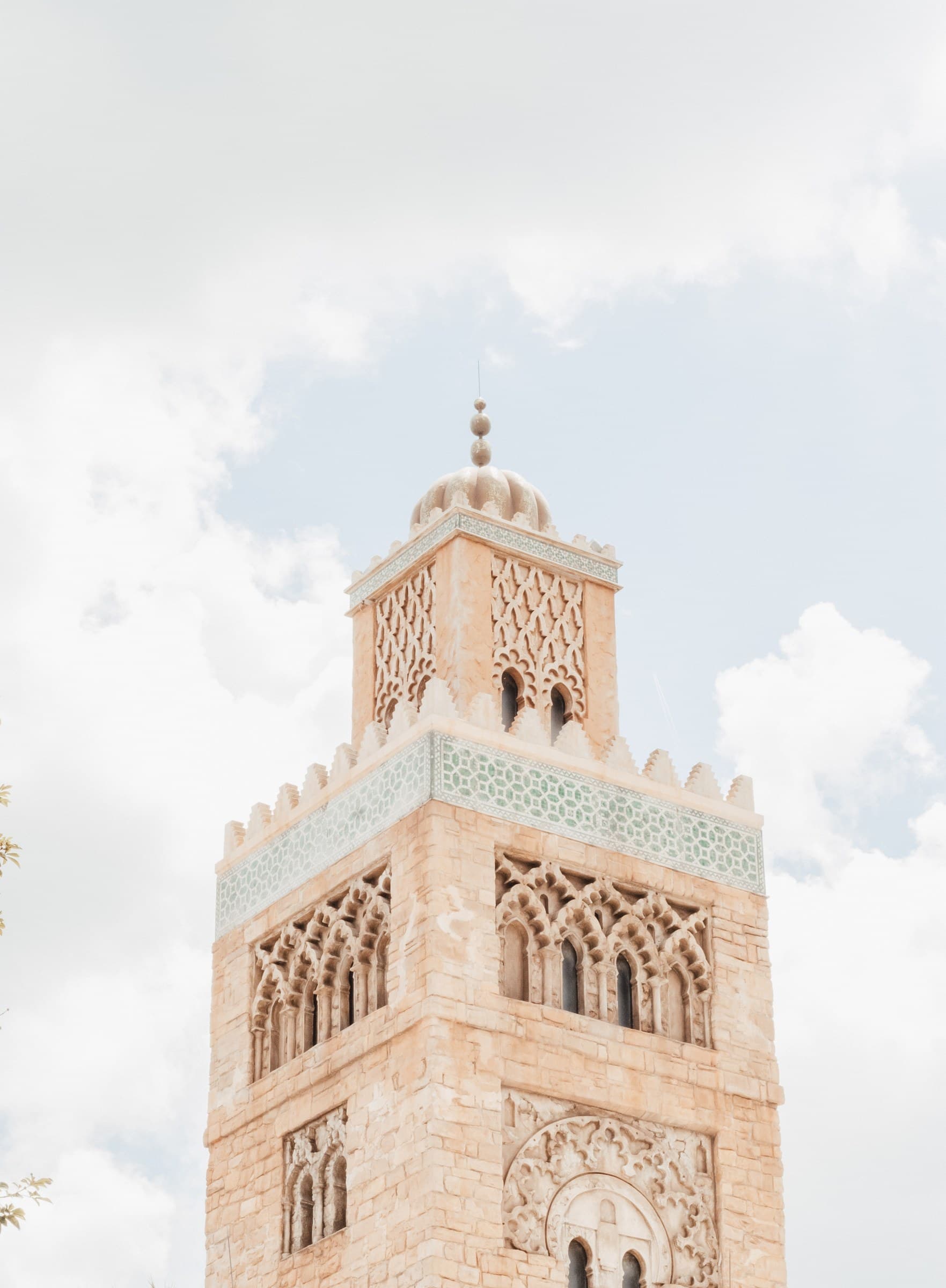 Minarete de la mezquita Koutoubia de Marrakech con ornamentación árabe en piedra rosada y cielo nublado